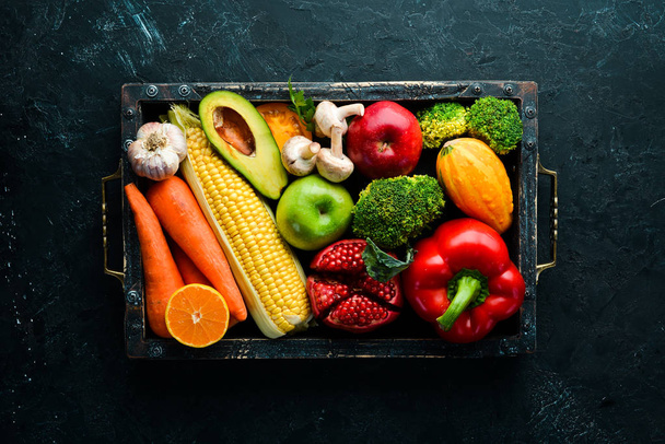 frisches Gemüse und Obst auf schwarzem Steinhintergrund. Gesunde Ernährung. Ansicht von oben. freier Kopierraum. - Foto, Bild