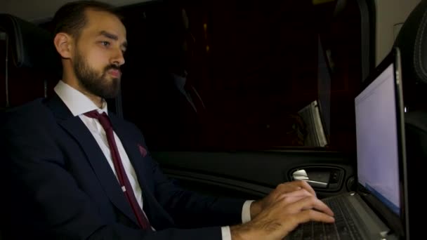 Successful businessman typing on his laptop on the backseat of his limousine - Séquence, vidéo