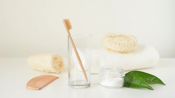 女性の手は浴室のガラスから竹の木製の歯ブラシを取ります。廃棄物・衛生コンセプトゼロ - 映像、動画