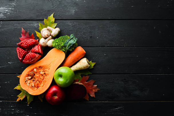 Verduras y frutas de otoño sobre un fondo de piedra negra: calabaza, tomates, maíz, granada, caqui, manzana. Vista superior. Espacio libre de copia
. - Foto, Imagen