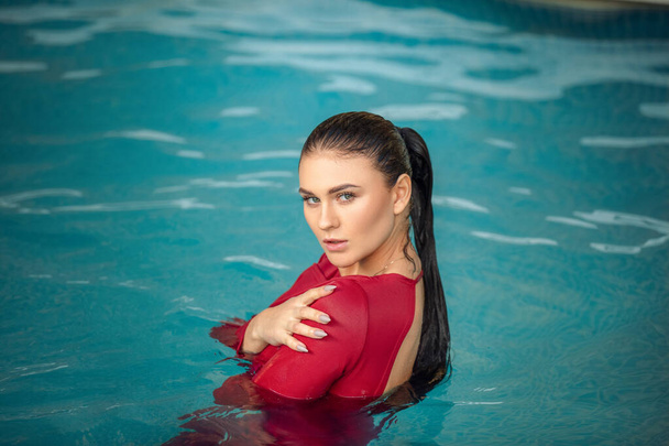 Young sexy woman floating on swimming pool in red dress. beauty shot - Photo, Image