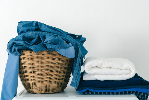 Close up clothes in basket and pile fabric on washing machine wi - 写真・画像