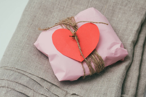 Soft pouch wrapped in craft paper and tie cord. Big red carton heart post card. Crumpled paper background texture. Delivery service. Online shopping. - Φωτογραφία, εικόνα
