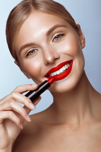 Beautiful girl with red lips and classic makeup with lipstick in hand. Beauty face - 写真・画像