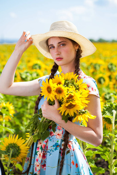 Portrait of a young beautiful girl in a field of sunflowers - Photo, image