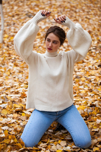 Young beautiful girl in blue jeans and gwhite sweater  - Fotoğraf, Görsel