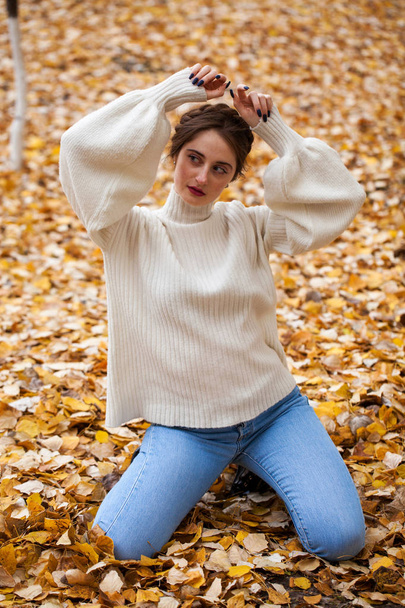 Young beautiful girl in blue jeans and gwhite sweater  - Foto, afbeelding