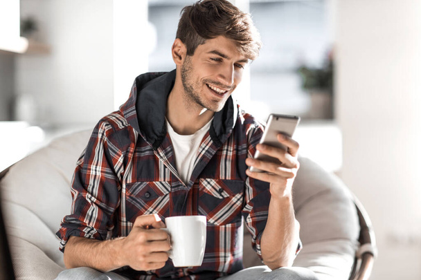 attractive young man drinking coffee and reading SMS. - Foto, Bild