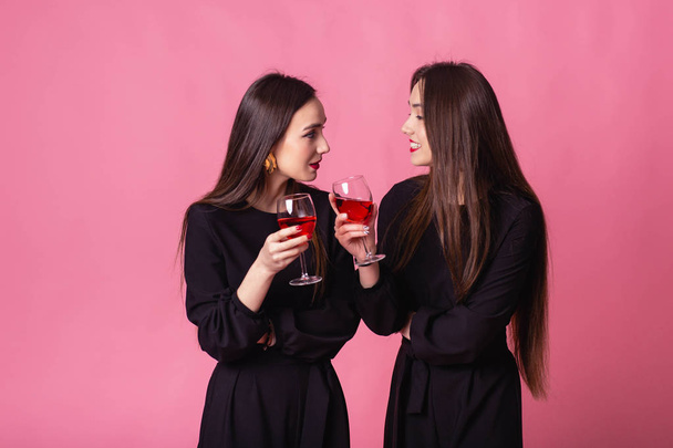 Две красивые девочки-близнецы празднуют корпоративный Новый год, пьют вино и разговаривают
 - Фото, изображение