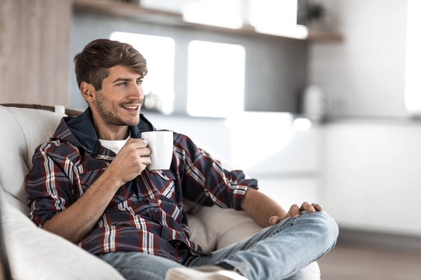 young man with a Cup of coffee in the background in the kitchen - Photo, image
