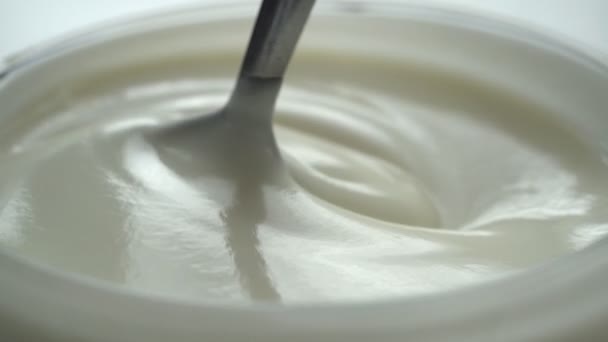 macro - video schieten, slow motion van het mengen van yoghurt met lepel in de beker - Video