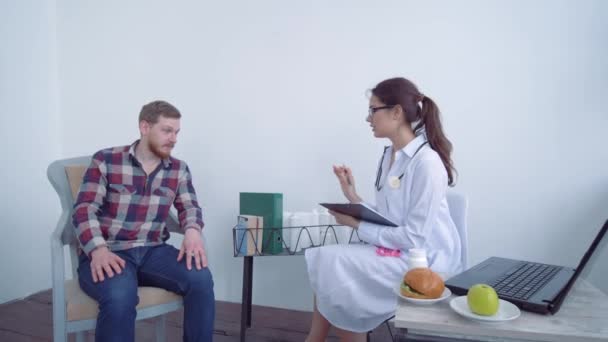 Gesundheitsversorgung, junger Patient berät sich mit Arzt über Gewichtsverlust und richtige Ernährung und misst mit Maßband - Filmmaterial, Video