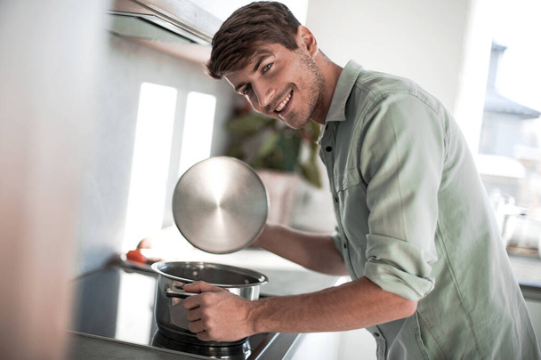 happy young man looking into a pot of delicious food. - Foto, Imagem