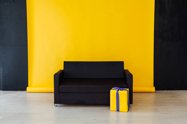 černá pohovka s dárky v interiéru místnosti se žlutým pozadím - Fotografie, Obrázek