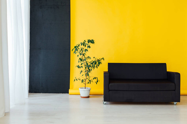 чорний диван в інтер'єрі кімнати з жовтим фоном
 - Фото, зображення