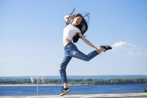 Young beautiful brunette woman posing against blue sky bright su - 写真・画像