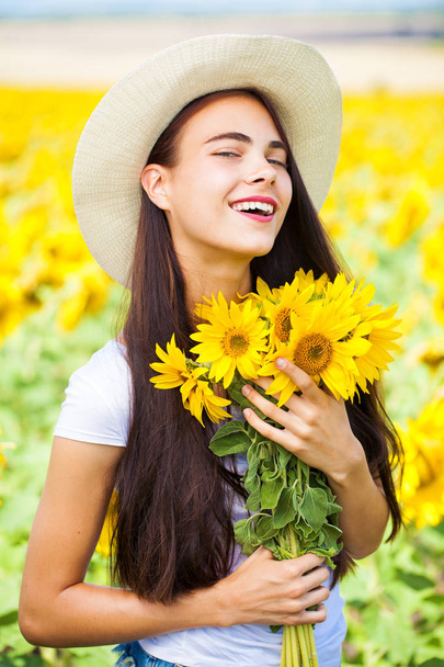 Portrait of a young beautiful girl in a field of sunflowers - Foto, Imagem