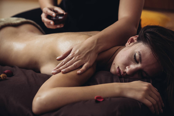 Sensuele tantrische massage in de gezellige sfeer van een schoonheidssalon door een professionele massagetherapeut - Foto, afbeelding