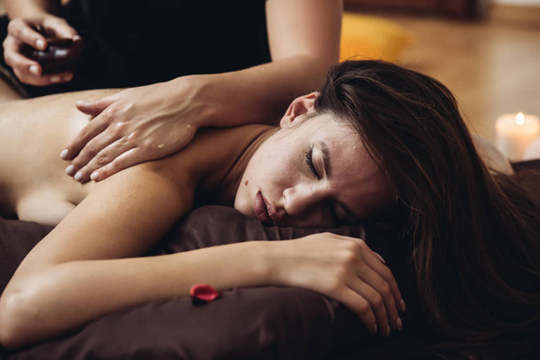 Sensuele tantrische massage in de gezellige sfeer van een schoonheidssalon door een professionele massagetherapeut - Foto, afbeelding