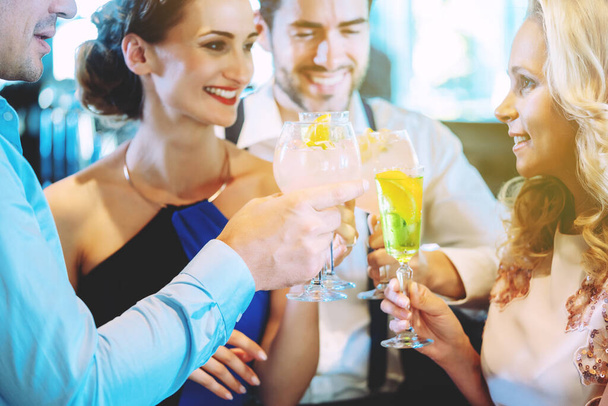 Мужчины и женщины за стойкой бара наслаждаются напитками - Фото, изображение