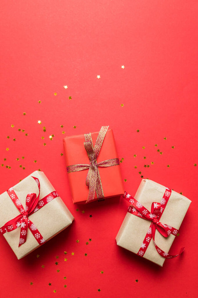 Modern gestaltete bunte Papier-Überraschungsschachteln mit goldglänzenden Schleifen auf rotem Hintergrund. Geburtstagsbanner, Foto für Artikel, Geburtstagsposter oder Postkarte - Foto, Bild