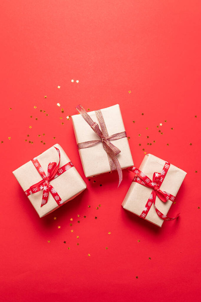 Composizione creativa con scatola regalo rossa, nastri decorazioni natalizie su sfondo rosso
 - Foto, immagini
