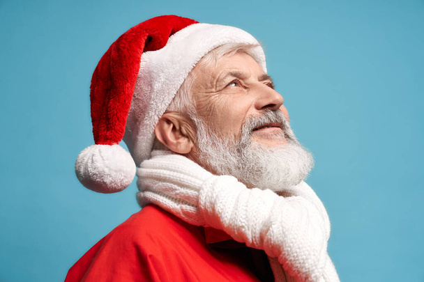 Side view of Santa Claus in hat and white scarf looking up - Foto, immagini