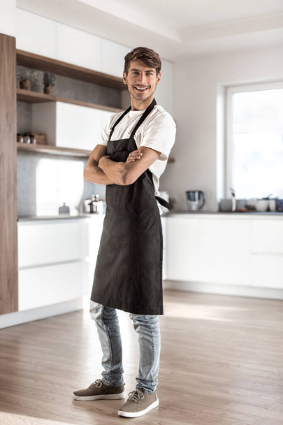 in full growth. attractive young man standing in home kitchen - Zdjęcie, obraz