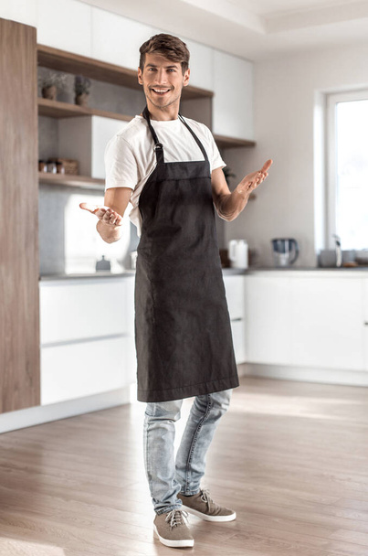 in full growth. attractive young man standing in home kitchen - Fotoğraf, Görsel
