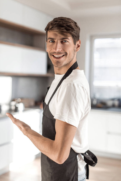 in full growth. attractive young man standing in home kitchen - Foto, Bild