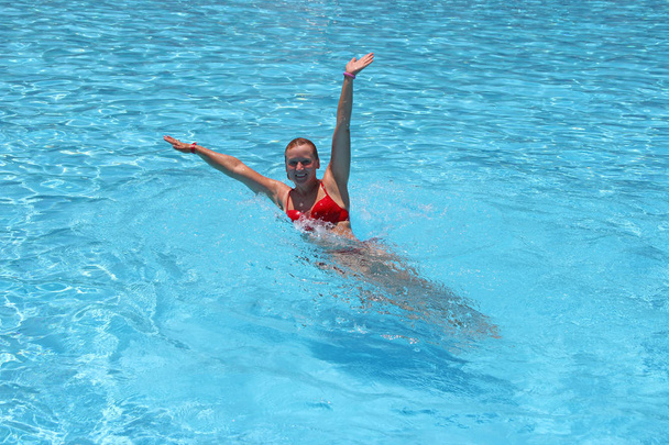 Привлекательная женщина плавает в бассейне во время отпуска. Прыжки в бассейн
 - Фото, изображение