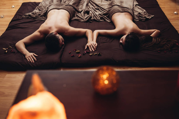 Ontspannende massage voor een paar in vier handen. Vierhandige massage is een massage waarbij twee therapeuten tegelijkertijd aan je werken en elkaar spiegelen.. - Foto, afbeelding