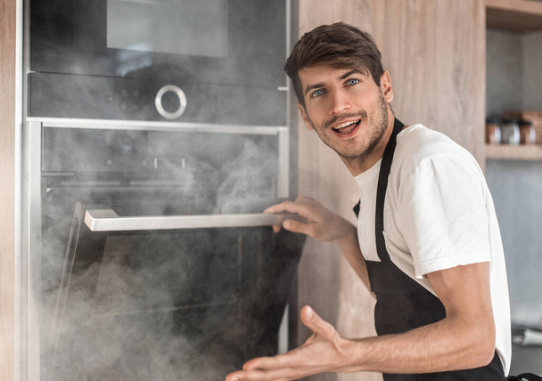 emotional young man standing near broken oven - Fotoğraf, Görsel