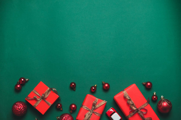 Kreativní složení vánočních dárkových krabic se stuhami a míčky na zeleném pozadí. Rekreační banner pro webové stránky. Složení plochého stylu, pohled shora. - Fotografie, Obrázek