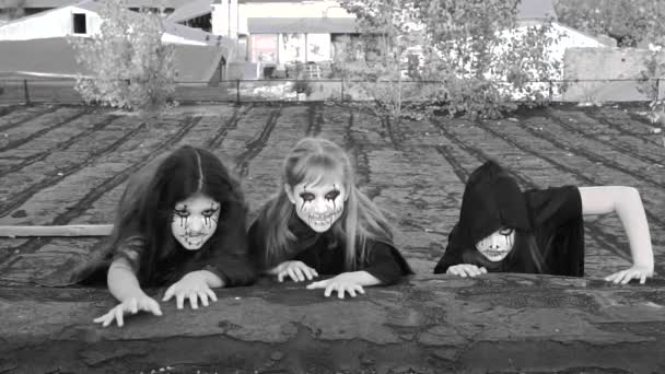 Három zombi jelmezes tinilány mászkál végig egy régi romos épület tetején, és ijesztően néz a kamerába. Lassú mozgás. Fekete-fehér videó. - Felvétel, videó