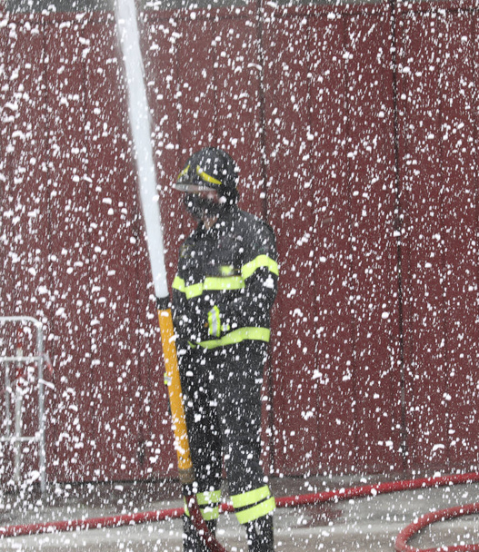 πυροσβεακός μαχητής χρησιμοποιεί αφρό κατά τη διάρκεια της φωτιάς - Φωτογραφία, εικόνα