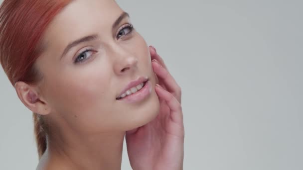 Studio portrait of young, beautiful and natural redhead woman applying skin care cream. Face lifting, cosmetics and make-up. - Filmagem, Vídeo