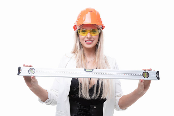 Sexy blonde posing in orange construction helmet, goggles and holding a construction level - Fotó, kép