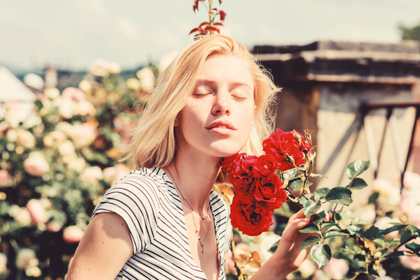 sexy girl with red rose. beautiful woman with blonde hair in garden. natural beauty. Spa and skincare. summer and spring park nature. rose flower smell. Parfume. relaxing in morning - Фото, изображение