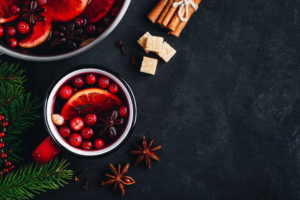 Mulled Wine Hot Drink with Cranberries, oranges, apples and spices on dark concrete background.  - Zdjęcie, obraz