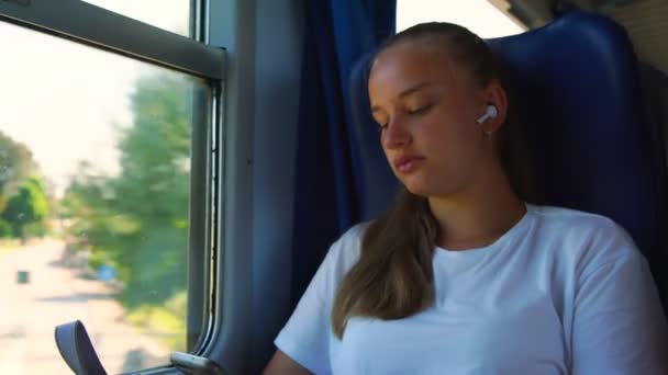 cute girl listens to music on phone with headphones closeup - Záběry, video