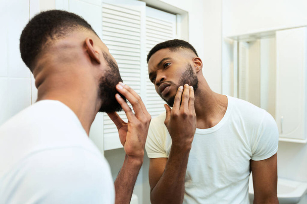 ustaraný africký muž dívá v zrcadle v koupelně - Fotografie, Obrázek