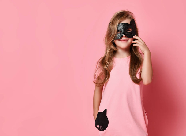 Christmas and New Year concept. Smiling kid girl in cat mask and cute pink dress with cat print is ready for carnival - Foto, imagen