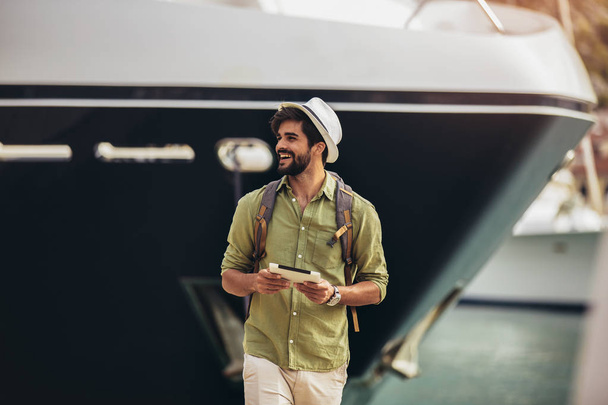 Hombre joven caminando por el puerto de un complejo turístico de mar con b
 - Foto, Imagen