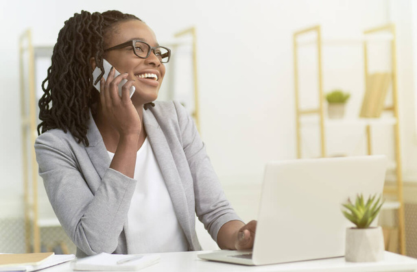 Afro Girl Talking On Phone Sitting At Laptop In Office - Fotografie, Obrázek
