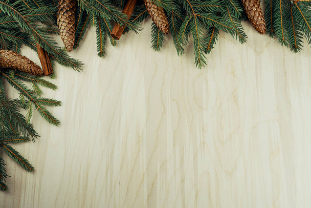 Χριστουγεννιάτικο καρέ φτιαγμένο με κλαδιά, κώνους και κανέλα σε ξύλινο φόντο - Φωτογραφία, εικόνα