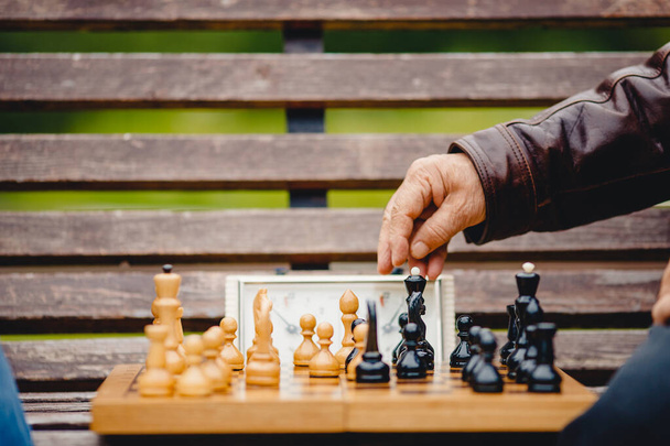 Homme âgé senior tient pièce d'échecs plateau de jeu en plein air
 - Photo, image