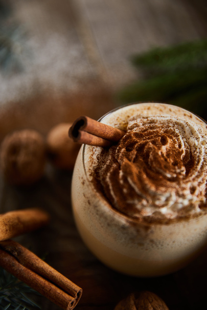 close up view of tasty eggnog cocktail with whipped cream near cinnamon sticks - Fotoğraf, Görsel