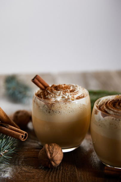 delicious eggnog cocktail with whipped cream, cinnamon sticks and wallnuts on wooden table isolated on grey - Zdjęcie, obraz