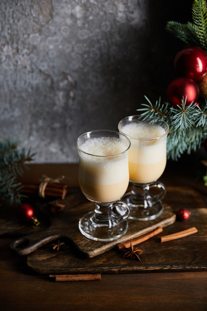 traditional eggnog cocktail on cutting board near decorated spruce branches on grey stone background - Photo, Image